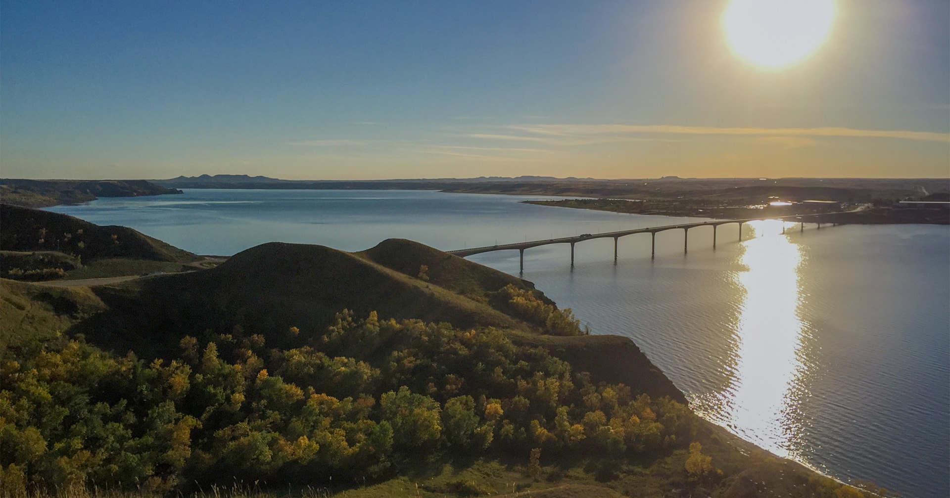 Large bridge over water with green trees and hills